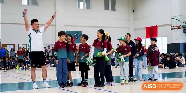 A group of students wearing matching team uniforms enjoys a moment of teamwork in the gym at Xi_an Hanova International School.