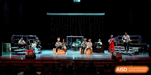 Students perform a theatrical skit on a large stage featuring creative props and festive decorations at Xi_an Hanova International School.