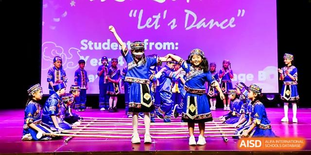 Two young students in traditional blue costumes perform a dance routine for a "Let's Dance" event at Xi_an Hanova International School.