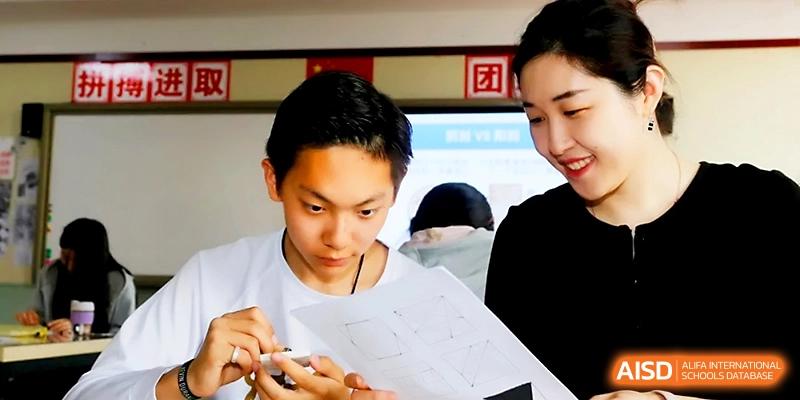 A student and a teacher look closely at a document together during a focused classroom lesson at Beijing Xicheng Academy.