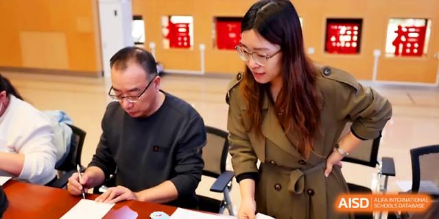 A male staff member and a female student discuss work while reviewing papers at a desk at Beijing Xicheng Academy.