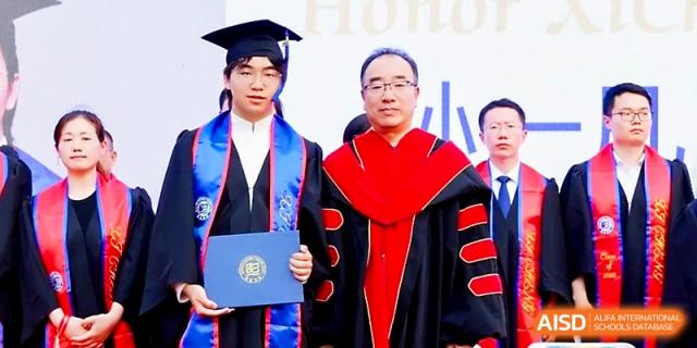 A graduate in a blue gown stands proudly next to a faculty member in red regalia during a ceremony at Beijing Xicheng Academy.