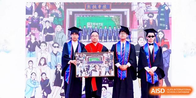 Two graduates and a faculty member hold a large framed commemorative photo during a graduation event at Beijing Xicheng Academy.
