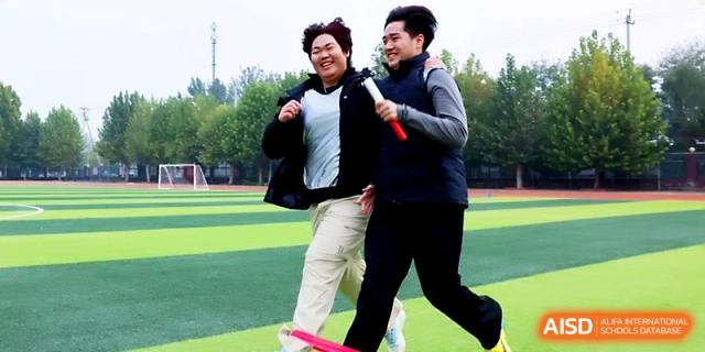 Two young men smile while participating in a coordinated race event during the school's sports day at Beijing Xicheng Academy.