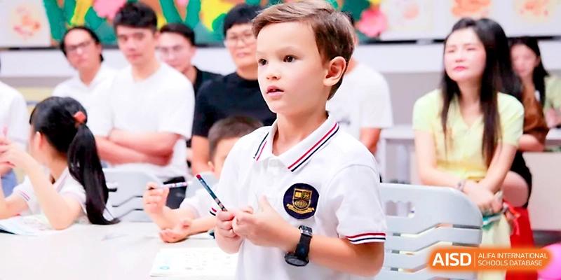 A young student in a white polo shirt stands confidently to speak during a class discussion at Yangjiang Yangdong Eone school.