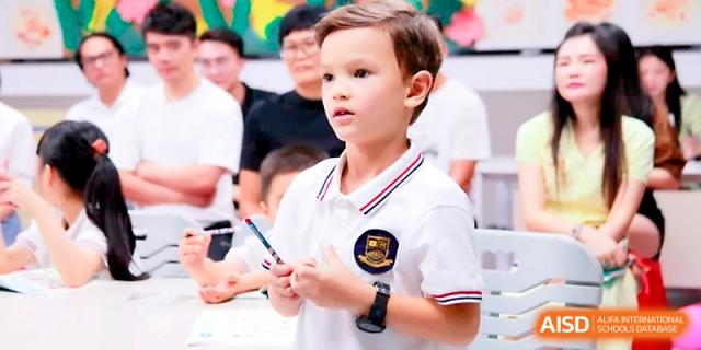A young student in a white polo shirt stands confidently to speak during a class discussion at Yangjiang Yangdong Eone school.