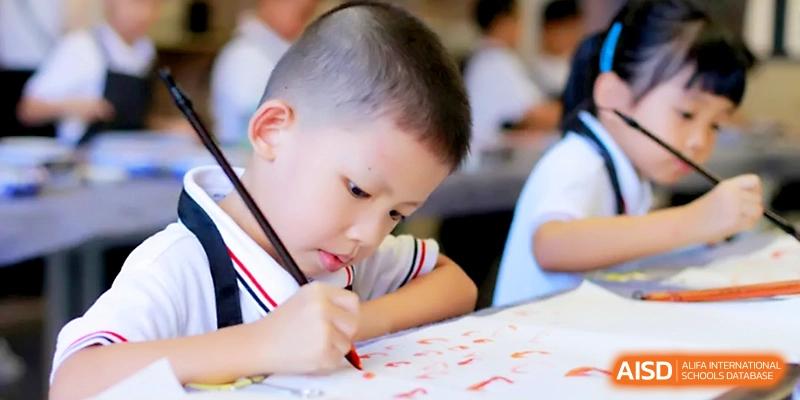 A young boy focuses intently on his drawing, using a red marker to create art in class at Yangjiang Yangdong Eone school.