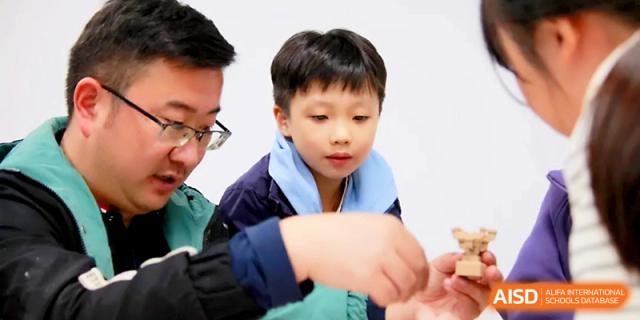 A teacher and student work together closely on a hands-on building project in the classroom at Yangjiang Yangdong Eone school.