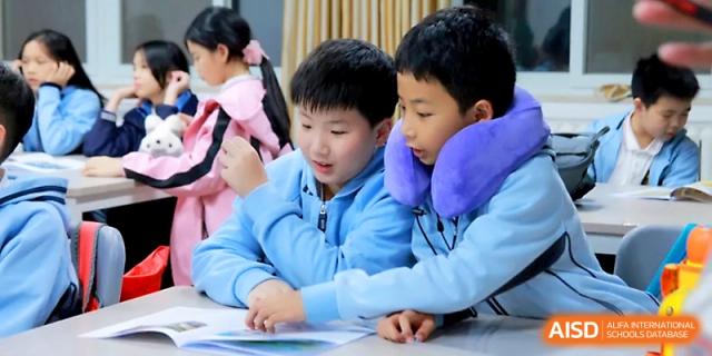 Two students in blue jackets collaborate on a task, looking down at their shared workspace at Yangjiang Yangdong Eone school.