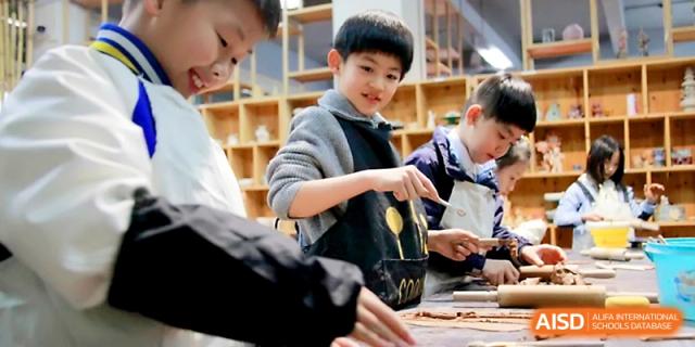 A young boy smiles while participating in a creative arts and crafts session with his peers at Yangjiang Yangdong Eone school.