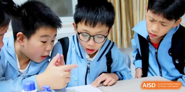 A student with glasses looks thoughtfully at his notebook while working on an assignment at Yangjiang Yangdong Eone school.
