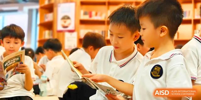 A group of students in white uniforms gather around to read and discuss a book together at Yangjiang Yangdong Eone school.