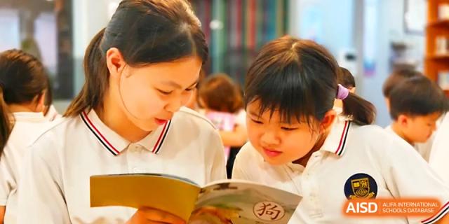 A teacher leans in to read a book alongside a young student, encouraging a love for literacy at Yangjiang Yangdong Eone school.