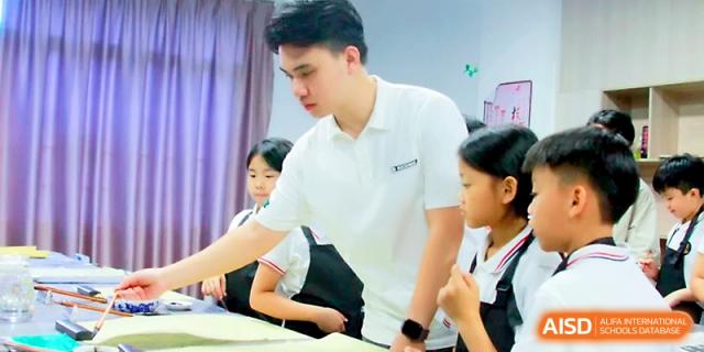 A male teacher stands at a desk, providing guidance to a group of focused students during class at Yangjiang Yangdong Eone school.