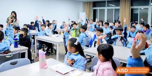 Many students raise their hands eagerly to answer a question during a lively classroom lesson at Yangjiang Yangdong Eone school.