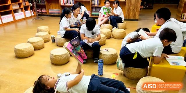 Students relax on floor cushions in a cozy library setting while enjoying their favorite books at Yangjiang Yangdong Eone school.