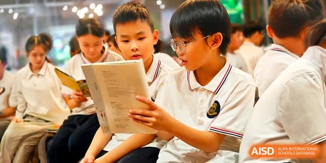 Two students hold a book together, practicing their reading skills in a supportive environment at Yangjiang Yangdong Eone school.
