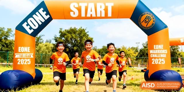 A group of excited students in matching orange shirts cross the starting line of a race during sports day at Yangjiang Yangdong Eone school.