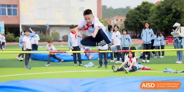 A student successfully clears a high jump bar over a blue landing mat during a track and field event at Yangjiang Yangdong Eone school.
