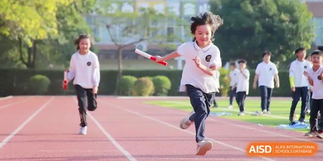 A young girl runs with great speed and focus during a relay race on the outdoor athletics track at Yangjiang Yangdong Eone school.
