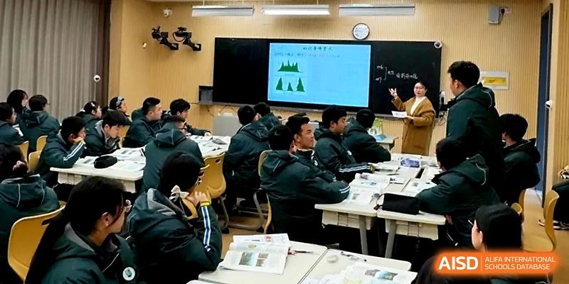 A teacher uses a large screen to explain a lesson to a classroom full of attentive students in green jackets at Yangzhou Shuren High School.