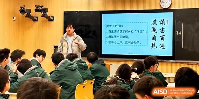 A student stands at the front of the class to present his work next to a digital screen displaying lesson notes at Yangzhou Shuren High School.
