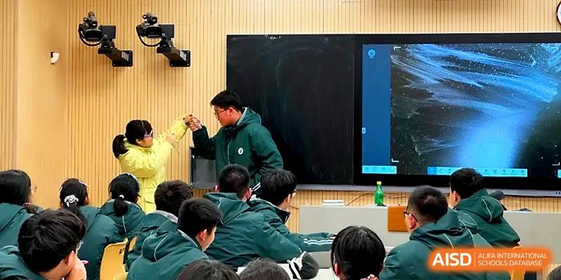A teacher in a green jacket leads a demonstration at the front of a classroom using a large digital screen at Yangzhou Shuren High School.
