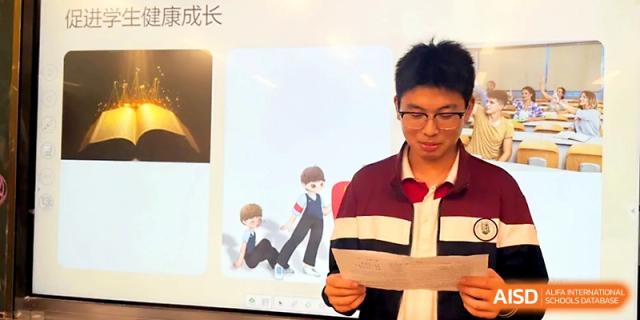 A young boy in a maroon jacket reads from a script while presenting a project in front of his peers at Yangzhou Shuren High School.