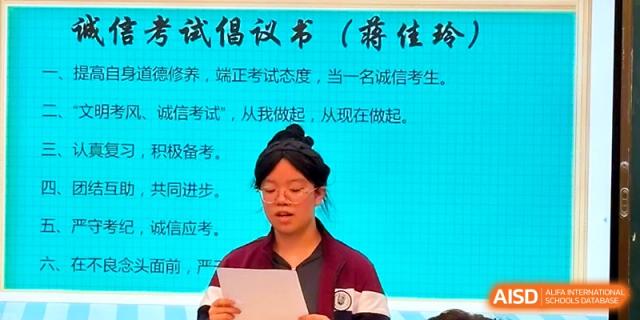 A student stands before a large screen displaying text to lead a speech or announcement for the class at Yangzhou Shuren High School.