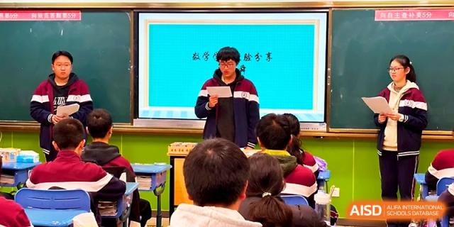 A student presents in front of the classroom while classmates listen, with educational content shown on the screen at Yangzhou Shuren High School.