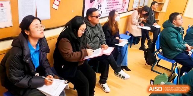 Educators or parents sit together in a classroom, taking notes during a school meeting or observation session at Yangzhou Shuren High School.
