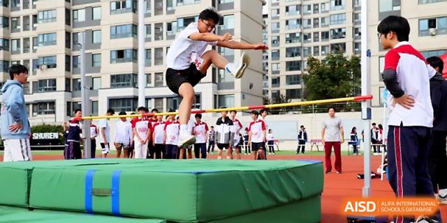 A student athlete clears the bar during a high jump competition on a sunny day at the athletics field of Yangzhou Shuren High School.