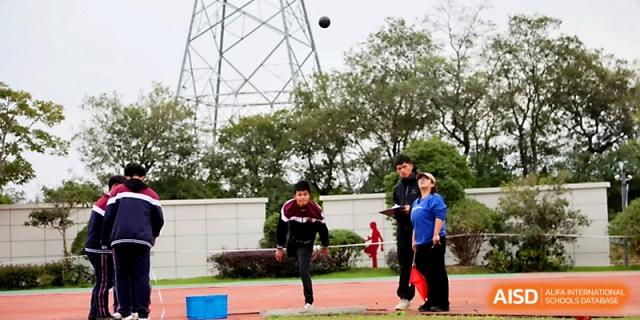 A student participates in a shot put competition during an outdoor track and field event on the campus at Yangzhou Shuren High School.