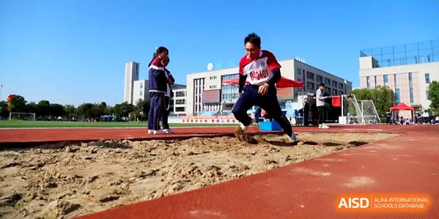 An athlete prepares to land in the sand pit during a long jump event at the school's annual sports competition at Yangzhou Shuren High School.