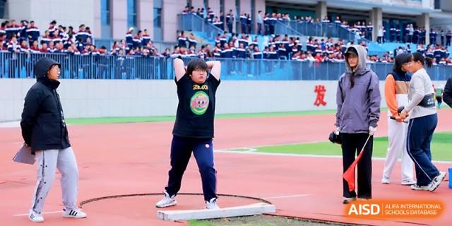 A student athlete prepares to throw a shot put during an outdoor track and field event on the school's athletic grounds at Yangzhou Shuren High School.