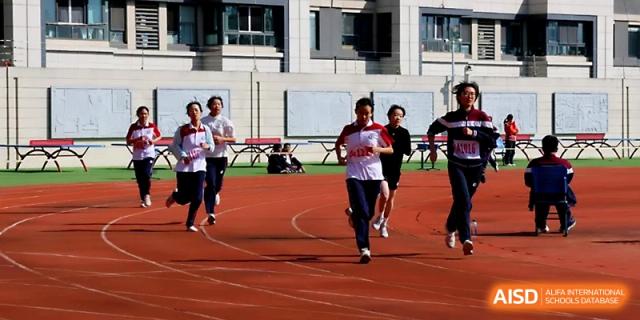 Female students in sports uniforms race down the red running track during a competitive sprint event at Yangzhou Shuren High School.