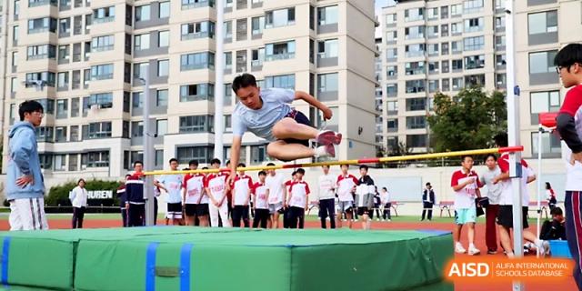 A focused student athlete jumps high over the bar during a track and field high jump event held at Yangzhou Shuren High School.