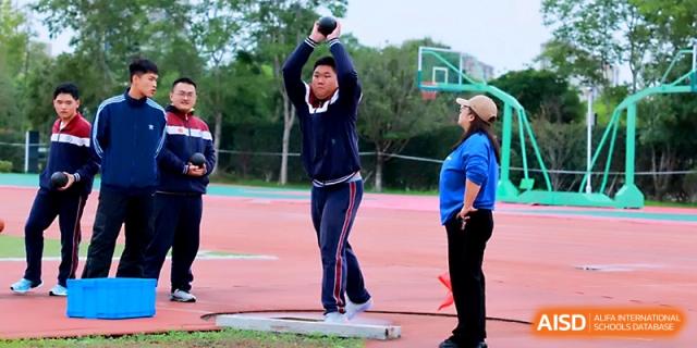 A student in a navy track suit puts all his strength into a shot put throw during an outdoor sports competition at Yangzhou Shuren High School.
