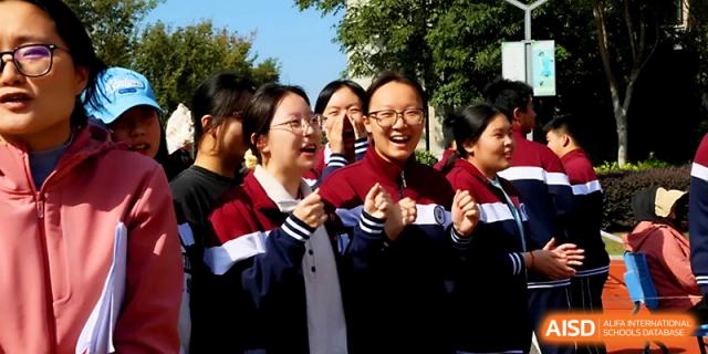 A group of female students in school uniforms smile and cheer enthusiastically for their classmates at Yangzhou Shuren High School.