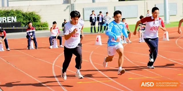 Two male students compete in a fast-paced sprint race on the outdoor athletics track during a sports meet at Yangzhou Shuren High School.