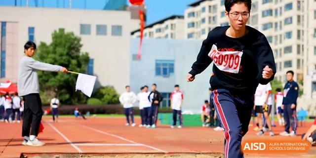A student athlete sprints with determination past the spectator area during a track event at Yangzhou Shuren High School.