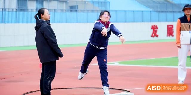 A female student athlete focuses on her form while throwing a shot put during a field competition at Yangzhou Shuren High School.