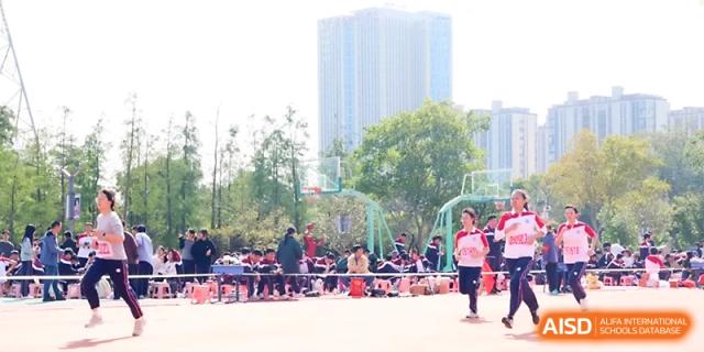 A wide shot of the outdoor sports field shows students participating in various track and field events at Yangzhou Shuren High School.