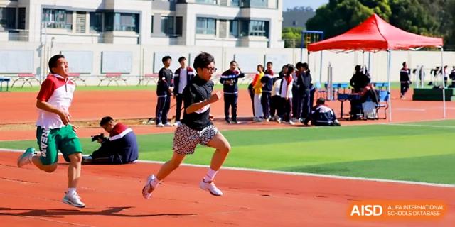 A student in a black shirt sprints down the track during a competitive racing event held at the sports field of Yangzhou Shuren High School.