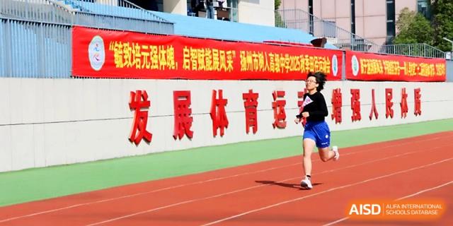 A lone runner sprints toward a large red banner during a track event at the annual sports festival of Yangzhou Shuren High School.