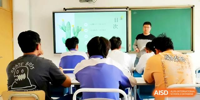 Students in blue and white jackets focus on a digital whiteboard presentation featuring educational graphics at Yinchuan No.1 High School.