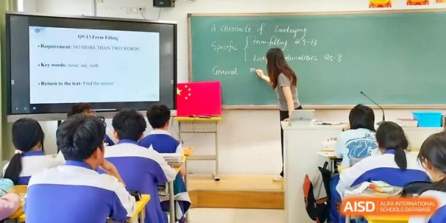 A teacher writes on a green chalkboard while students follow along during a traditional classroom lecture at Yinchuan No.1 High School.