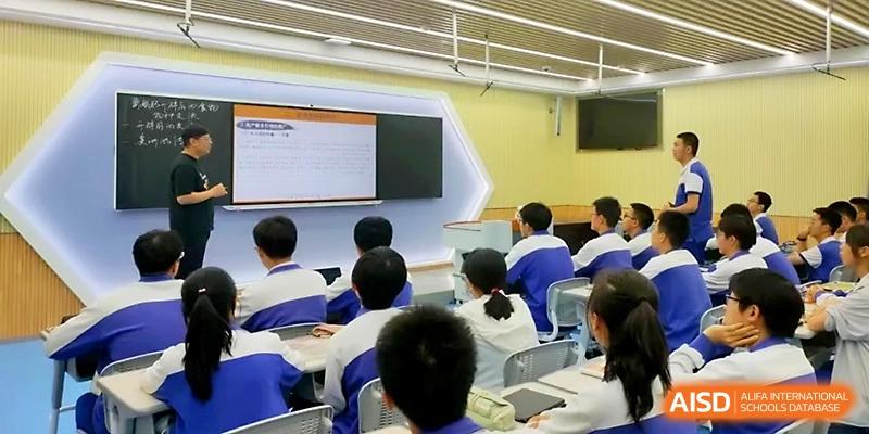 Students sit in a modern, well-lit lecture hall while viewing an informational presentation on a wide screen at Yinchuan No.1 High School.