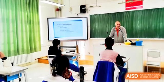 A foreign teacher leads a discussion in a bright classroom using a digital screen for visual aids at Yinchuan No.1 High School.