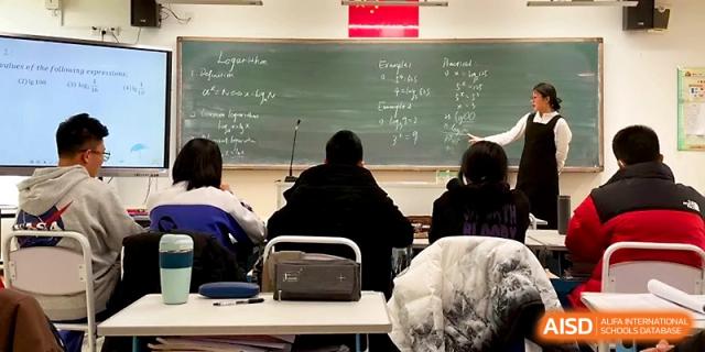 Students observe a chalkboard filled with notes as a teacher leads a technical lecture from the front of the room at Yinchuan No.1 High School.